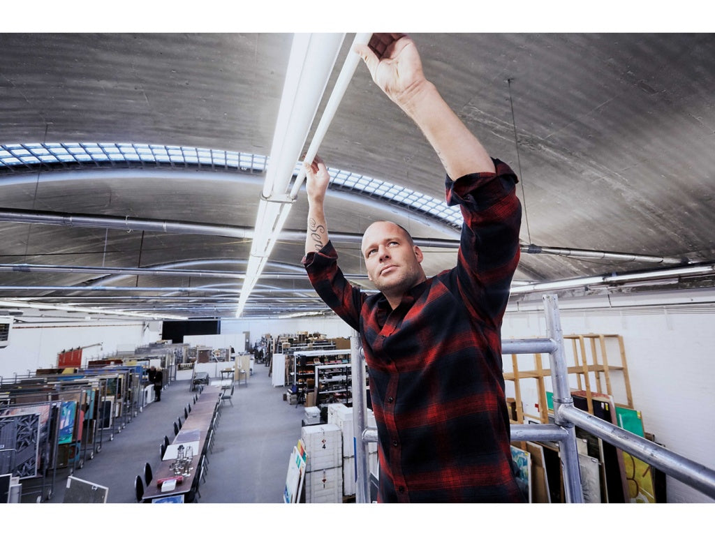 En man står på ställning i ett lager och byter lysrör T5 mot LED-Lysrör T5.