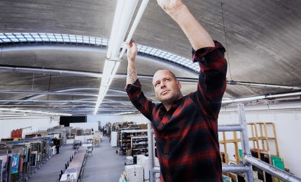 Man står med uppsträckta armar och håller på att byta lysrör mot mot LED-Lysrör i en lagerlokal.