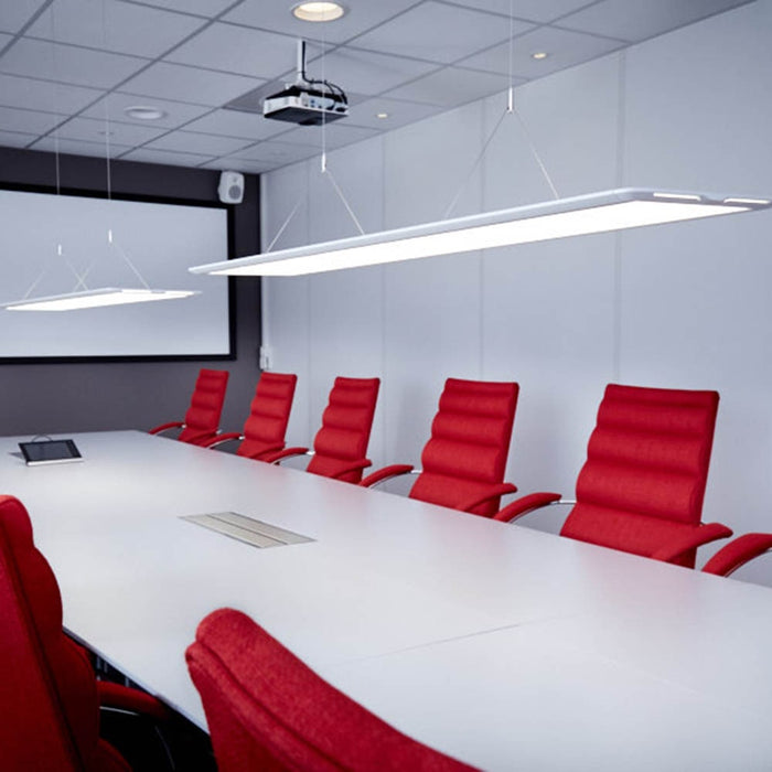 Moderna LED armaturer hänger ned i ett konferens- eller mötesrum. Avlångt bord med exklusiva stolar, de två avlånga belysningsarmaturerna ser ut att sväva ovanför bordet.
