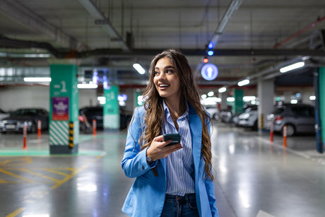 LED-Lysrör i ett garage. I förgrunden promenerar en kvinna med en mobiltelefon i handen. I bakgrunden syns garage med lysrörsarmaturer.